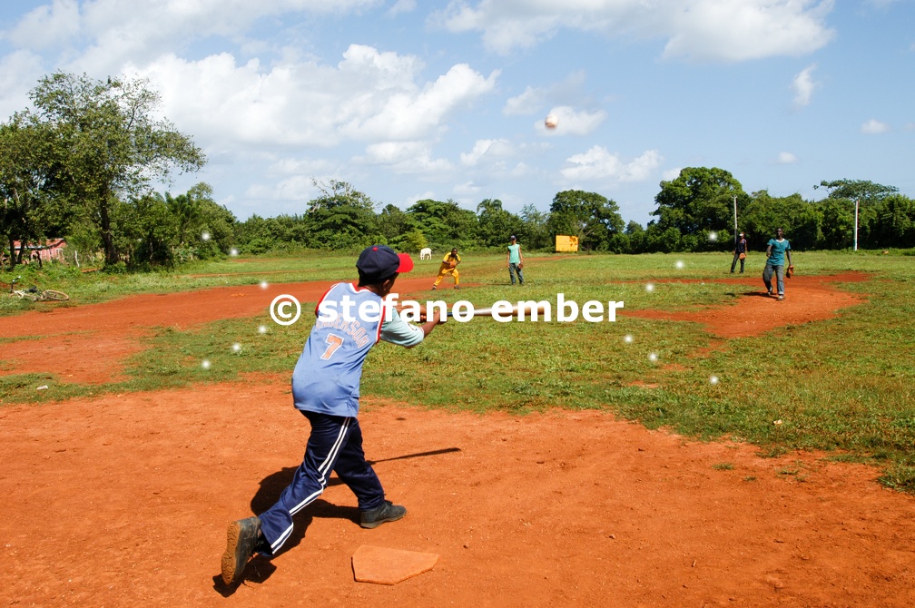 Boys playing baseball on a field at Las Galeras