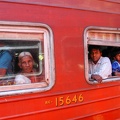 People who look out of the windows of the train that is carrying them to Kandy
