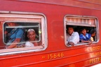 People who look out of the windows of the train that is carrying them to Kandy