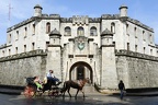 Tourists on a carriage pulled by a horse in front of a fort at Old Havana
