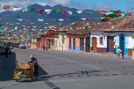 People walking in a street with numerous flags at San Cristobal de las Casas
